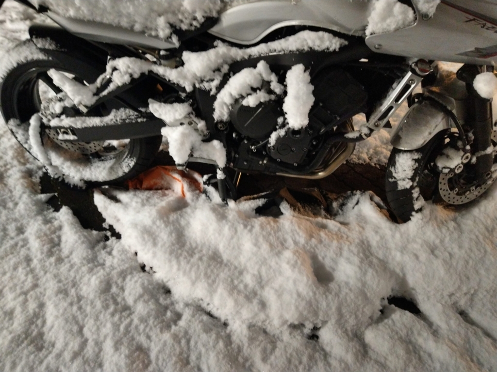 風で剥がれて車体の下で雪に埋もれていたバイクカバー